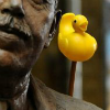 sunnymodffa: Close-up shot of a bronze and moustached statue. A yellow duckie on a stick emerges from behind his shoulder. (Duck on a Stick)