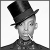 konsectatrix: An androgynous young black woman wearing a tophat, cigarette dangling from the corner of her mouth. (tophat androgyne)