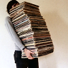 laulan: A photo of person holding a stack of books or records so tall you can't see their face. ([misc] little busy here)