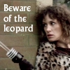 kalypso: Cally in her leopard coat and holding a Liberator gun, peering warily round the corner of Sarkoff's tower, captioned Beware of the Leopard (Cally)