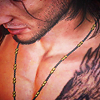 gifted: Gladio: detail of a downcast bare chested man with some tattoos visible (masc)