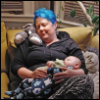 lifecollage: A woman with blue hair napping on a green couch, holding a sleeping baby (Napping with the Bean)