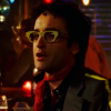 clarasteam: Man wearing big glasses, a red scarf and a jacket with a bright stripe down one shoulder (Darren s2)