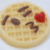 wafflelate: a waffle with a kissy face on it drawn with chocolate (smooch)