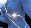 iodama: A woman's torso, stone, cracked, with light blazing forth from within her chest; a close up photo of Paige Bradley's sculpture, "Expansion", actually bronze not stone. (Default)