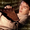 noxelementalist: BBC Merlin's Merlin, slumbering with a brown book resting on his chest; Welsh words hover in background (Emyrs)