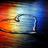 escriveine: A rainbow sheen overlays a heart drawn with water on a dark wood table. (color sheen heart)