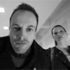 paradigm_shift: Elementary 1x13 Sherlock peering into the camera of the shell building set up by the NSA. Joan looks on in the background (Elementary: Peephole)