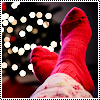 monksandbones: Crossed feet wearing red socks, resting on something, with Christmas tree lights in the background (holiday feets)