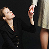 such_heights: a woman, sitting, holds a standing woman's hand (stock: make a stand [mignolagraphics])
