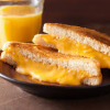 tropicsbear: Picture of a grilled cheese sandwich with a glass of juice in the background (Food: Grilled cheese sandwich)