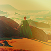 muccamukk: Wide shot Héloïse in her green dress standing on the beach looking at the waves. Light is golden and ethereal. (Lady on Fire: Seashore)