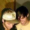 frausorge: Gabe Saporta in a dark shirt and gold cap, and Pete Wentz in a yellow shirt and dark bangs over his eyes, with their heads bent together looking downward (her hardest hue)