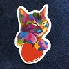 frausorge: a multicolored cat with perked-up ears and eyes peacefully closed, holding a red heart, against a dark blue background (set me as a seal)