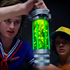 wolfish_willow: Steve Harrington and Dustin Henderson from Stranger Things holding a glowing green cylinder (Steve & Dustin bottle)