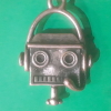 flowersforgraves: A small metal robot charm. The robot is wearing a headset with an attached microphone. (podfic: robot)