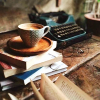inkstone: a pile of books, a cup of tea, and a typewriter (writing)