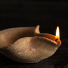 hlinspjalda: a small clay pinched-dish oil lamp, lit (lamp)