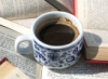 cafenowhere: a blue and white china cup of coffee on top of a pile of open books (coffee and books)