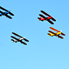 passingbuzzards: Four multicolored biplanes in blue sky (biplanes squadron)
