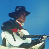linky: Ken sitting on a bulldozer while playing his guitar (Zubat: Hayakawa Ken)