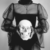 yarnofariadne: a woman in a sheer black dress holds a skull in front of her. (misc: one of those witches babe)
