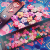 ai: a tin full of colorful konpeito candies and a bunch of floral jibbitz for crocs (konpeito and jibbitz)