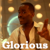 kalypso: The Fifteenth Doctor, Ncuti Gatwa, in front of the lights of the TARDIS interior, wearing an open shirt with a tie hanging down either side, and gesturing with two fingers together (Dr Gatwa)