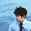 mumblemumble: bai yu in a light blue shirt and black tie, with the ocean in the background ([BY] by the sea)