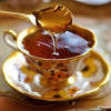 elf: A flowery teacup with a full spoon being held above it, dripping honey into the cup (Tea - Honey)