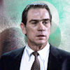 tarlanx: Sam Gerard head and shoulders wearing dark suit, white shirt and tie with a green textured background (Film - The Fugitive 2 - Sam Gerard)