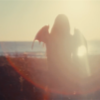 bluedreaming: a MEOVV member in silhouette looking away towards the sun, with bat wings (kpop - meovv toxic)