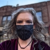 mareht: Woman in a gray fabric surgical style mask, with wavy dark blonde hair and swirly black eyeliner (Default)