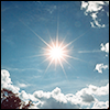 i_like_the_stars: The sun in a bright blue sky with some white clouds and a tree in the bottom left corner, shining with brilliance (MISC Sun)