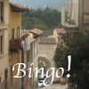 purplecat: A narrow street with plastered houses and an archway at the end.  The word Bingo! (genprompt_bingo)