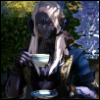 lilbittymonster: Kitali sitting with a cup of tea in one hand, looking at the camera and smiling knowingly. (Kitali)