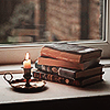 yarnofariadne: piled vintage books on a windowsill next to a black candleholder (misc: unwritten endings)