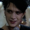 mews39: An old photo of Nicola Sirkis smiling with a microphone. He has short black hair and is wearing a ring earring, eyeshadow, and lipstick. (Default)