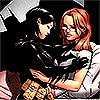 queenslayerbee: Cass, in her Batgirl suit with her mask off, leans over Barbara, who's sitting in bed. Cass looks at the bat in Barbara's chest, and Cass's shadow takes the shape of Batman in the wall behind her. (barbara and cass (dc comics))