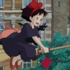 hexenprinzessin: Anime screenshot of a little witch with a happy expressionflying on a broomstick with a black cat on her shoulder, against a backdrop of brick buildings and trees. (kiki & jiji)