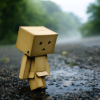 st_aurafina: a sad robot made of cardboard boxes, standing in the rain (Sad robot)