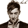 dapatty: Alan Cumming with a part of his neck tie in his mouth with the text "Heh". (Alan sepia heh)