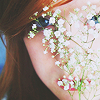 rainfall: A girl holds flowers in front of her face and peers through them. (little white flowers)