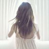 ext_4360: girl with long dark hair turned, back facing camera peeking through white curtains at the window (Default)