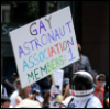 quadruplify: Gay pride parade participant, dressed as astronaut, holding sign that reads: "Gay Astronaut Association Members: 1" ([Other] LGBTQ+ - gay astronaut)
