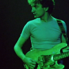 scaramouche: John Deacon wearing a tight shirt and playing bass guitar (john deacon tight shirt)