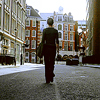ar: Evey Hammond in V for Vendetta (film) walks away from the camera on a road in London. (vfv - the city at sunrise)