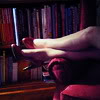 metatxt: legs wearing stiletto heels stretch across armchair in a library (art: literary legs)