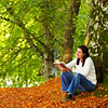 genarti: woman curled up with book, under a tree on a wooded slope in early autumn ([misc] my perfect corner of the world)