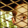 dearjohn: Part of a young man's face seen through the cage in a police car. (R - one)